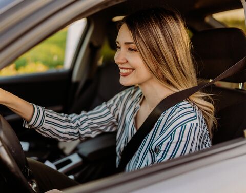 Una donna è seduta in macchina con la cintura di sicurezza allacciata.