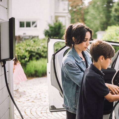 Une mère et son fils rechargent ensemble leur voiture électrique.