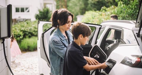 Une mère et son fils rechargent ensemble leur voiture électrique.