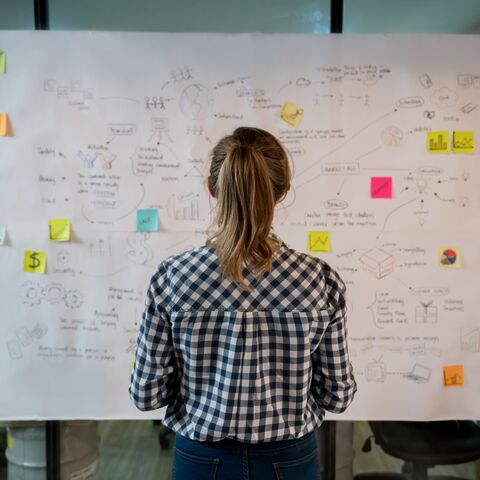 Una donna che abbozza un business plan su un cartellone in un ufficio creativo.