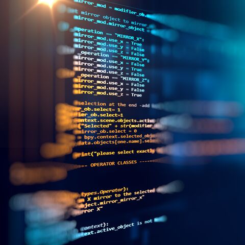 Gros plan d’un écran d’ordinateur avec code source en couleur sur fond sombre, partiellement flou et représentant la technologie moderne.