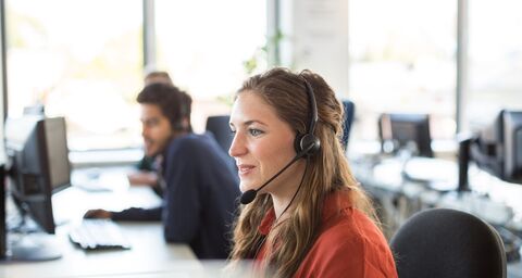 Una giovane donna con un headset sta ascoltando con attenzione un cliente nel Servizio clienti.