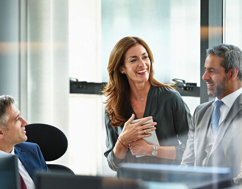 Eine Frau und ein Mann in Business-Kleidung im Gespräch an einem Meeting im Büro