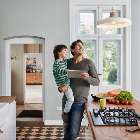 Father and son control a kitchen lamp via tablet.