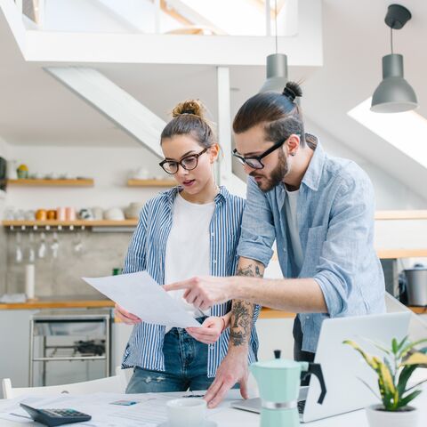 Un uomo e una donna sono in una cucina moderna e discutono di un documento che l’uomo ha in mano.