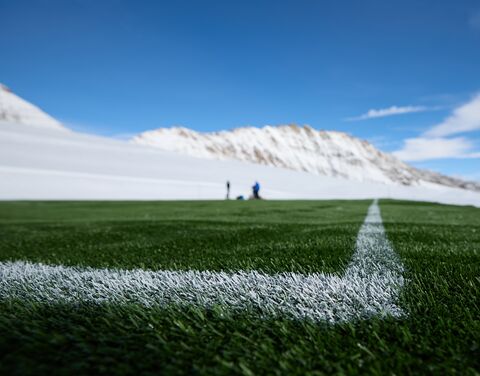 Ein Fussballfeld mit Bergen im Hintergrund.