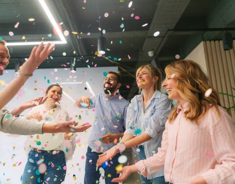 I collaboratori festeggiano con coriandoli in un ufficio.