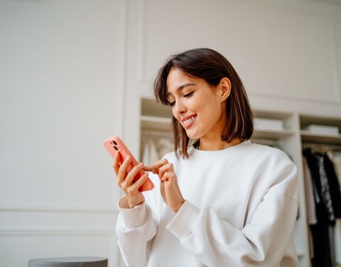 Une femme utilise son smartphone en souriant.