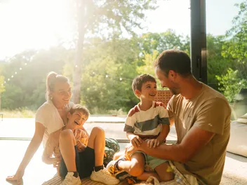 Eine Familie sitzt lachend im Wohnzimmer.
