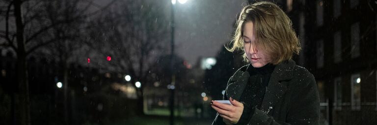 Nuit, une femme regarde son téléphone portable