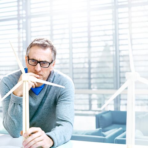 Ein Mann mit Brille arbeitet an einem Windradmodell.