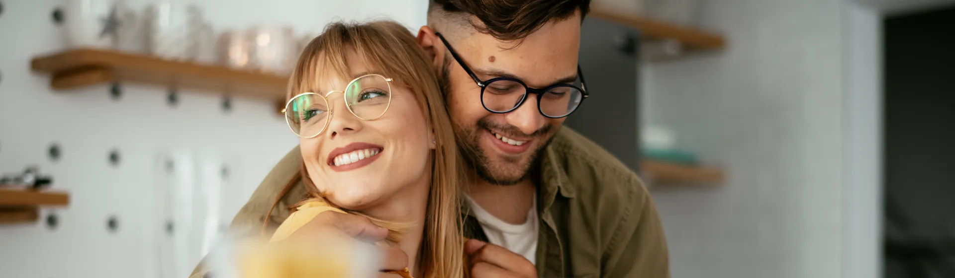 Young couple with glasses at kitchen table.