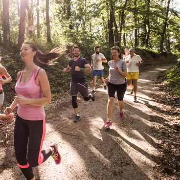 Eine Gruppe von Kollegen joggt durch einen Wald.