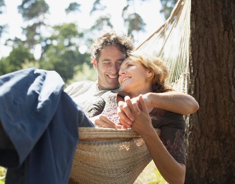 A couple is relaxing in a hammock in the garden, enjoying the day.