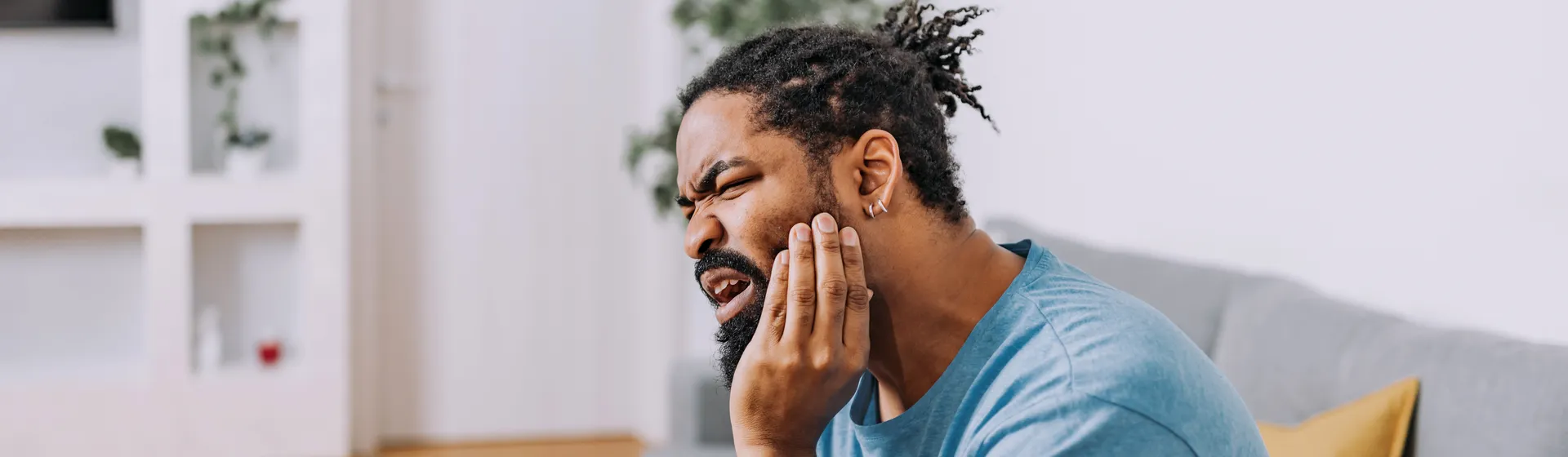 Portrait of a man holding his cheek because he is in pain.