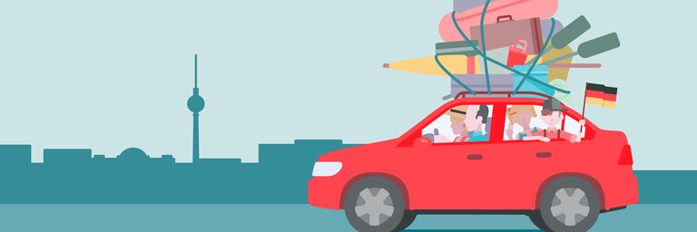 Une famille roule sur le toit d’une voiture rouge avec beaucoup de bagages, devant la silhouette de Berlin avec la tour de la télévision à l’arrière-plan.