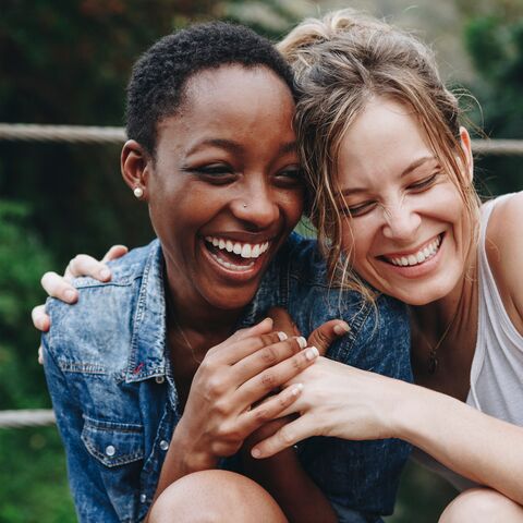 Portrait of two women hugging and laughing.