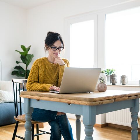 Une jeune femme travaille chez elle sur son ordinateur portable