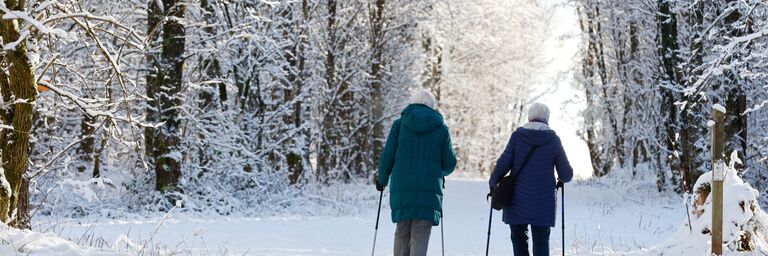 Zwei Frauen spazieren durch einen verschneiten Wald